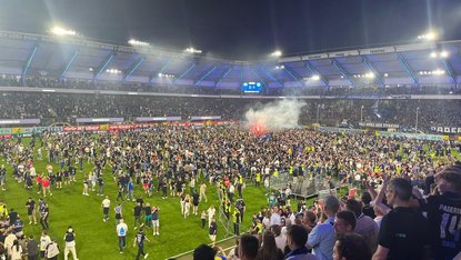 Bild aus einem Fußballstadion, wie viele Fans auf dem Fußballplatz stehen